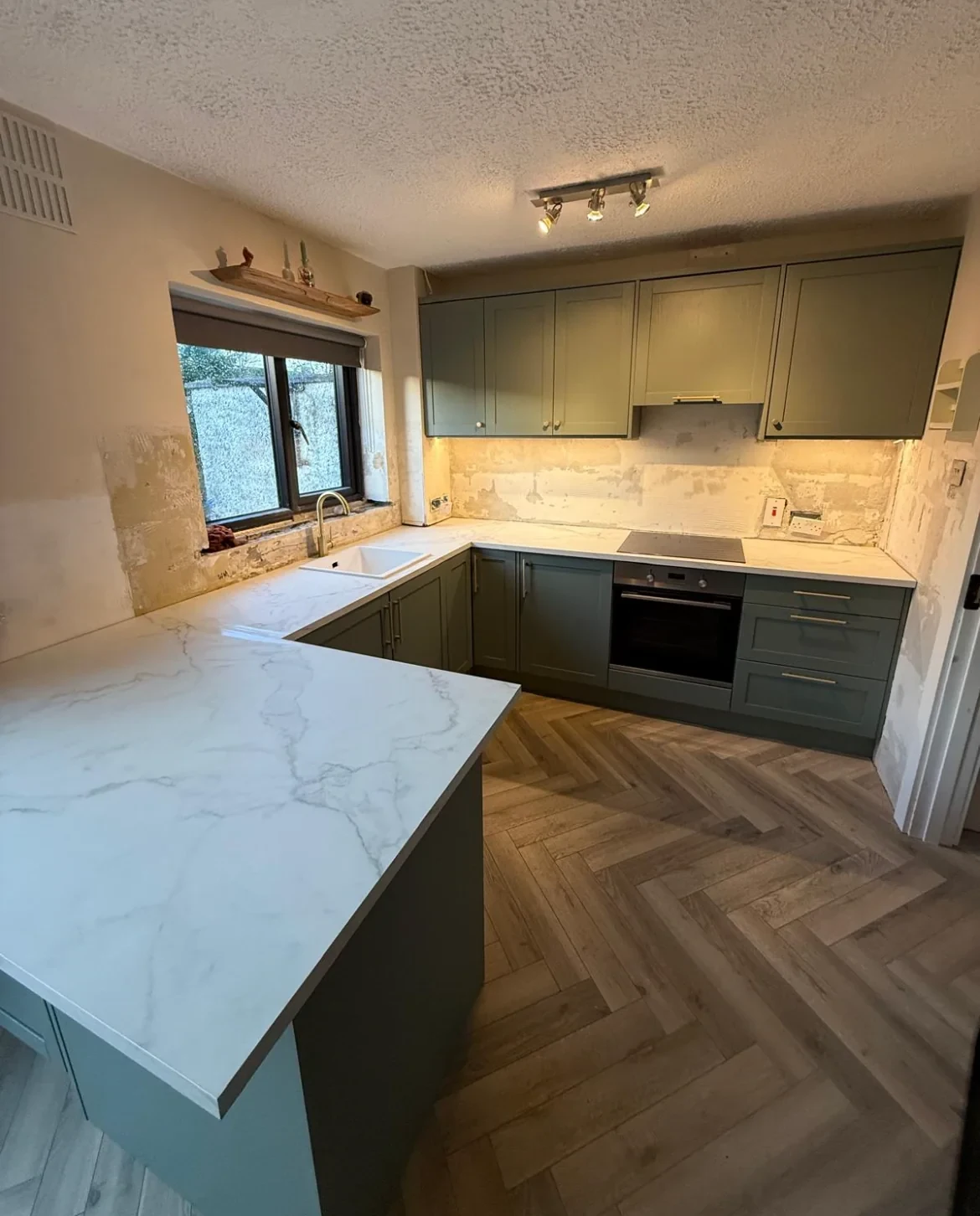 Warm green kitchen refurbishment with marble-effect worktops